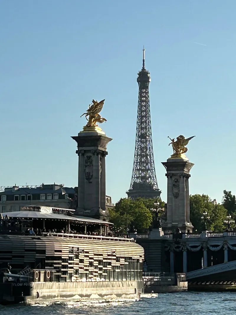 The gilded statues of Pont Alexandre III with the Eiffel Tower between them, seen from the river