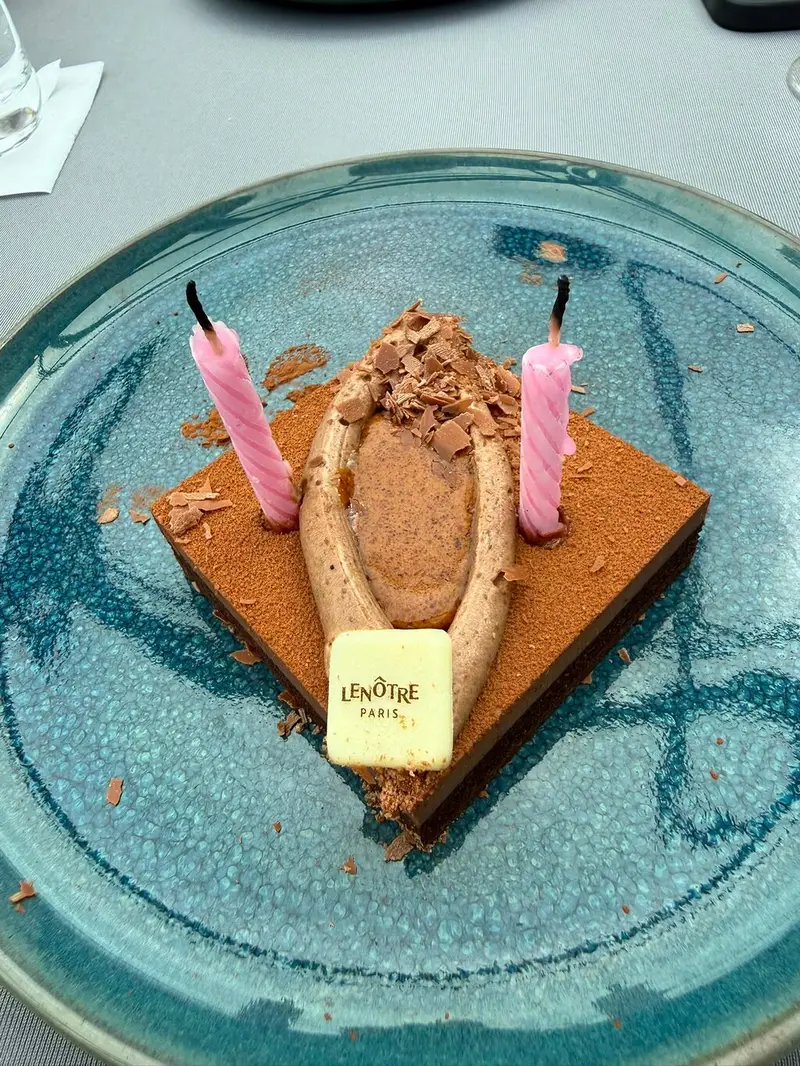 A chocolate dessert with two pink birthday candles and a white chocolate plaque
